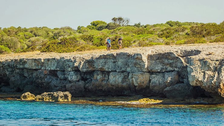 Zwei Urlauber wandern entlang der menorquinischen Küste