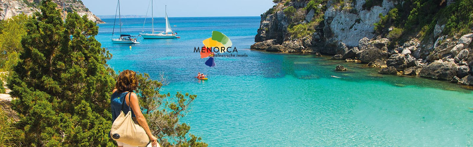 Berühmte Bucht Menorca mit türkisem Meer, grüner Natur und Selgelbooten
