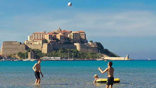 Zwei Urlauber spielen Volleyball am Strand von Calvi im Meer