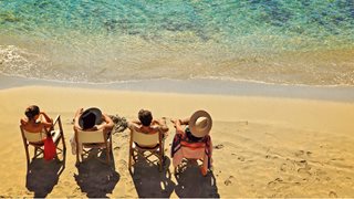 Vier Freunde sitzen in ihren Stühlen am Strand