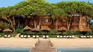 Hotel am Sandstrand mit Sonnenliegen und Schirmen
