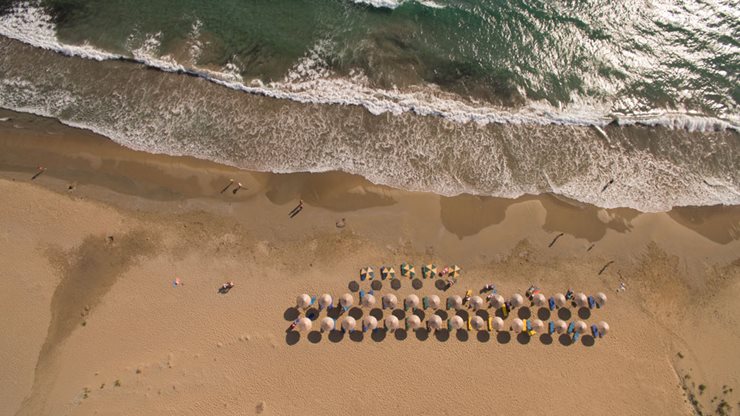 Griechischer Sandstrand auf Kefalonia mit Sonnenschirmen und leichtem Wellengang