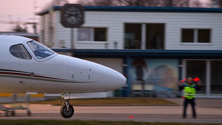 Kleines Flugzeug wird von einer Sicherheitskraft am Flughafen eingewiesen