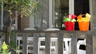 Sandspielzeug mit Eimern stehen auf der Terrasse einer Ferienwohnung