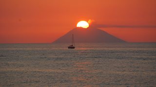 Die Sonne geht in der Ferne hinter der Vulkaninsel Stromboli unter