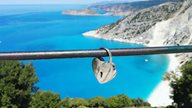 Liebesschloss hängt an Brücke mit Panoramablick auf den Myrtos Beach