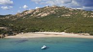 Blaues Meer vor flach abfallendem Strand und üppig grüner Vegetation